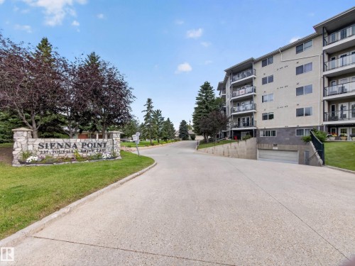 Multi-story building featuring balconies with glass railings, an underground garage, and a stone-clad entry sign - #314 237 Youville Dr E Nw, Edmonton, AB - Outdoor With Balcony