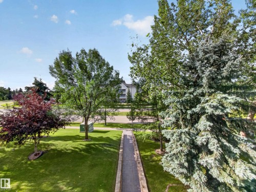 Manicured lawn with mature trees and a paved walkway - #314 237 Youville Dr E Nw, Edmonton, AB - Outdoor With View