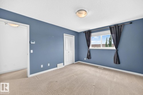 Carpeted flooring with a large window, a closet with bi-fold doors, and a flush mount ceiling light fixture - 217 Silverstone Crescent, Stony Plain, AB - Indoor Photo Showing Other Room