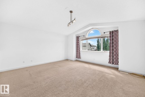 Angled wall with an arched window, track lighting fixture, and carpet flooring - 217 Silverstone Crescent, Stony Plain, AB - Indoor Photo Showing Other Room