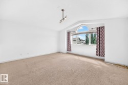 Angled wall with an arched window, track lighting fixture, and carpet flooring - 