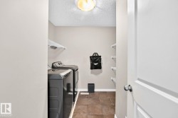 Laundry area featuring tile flooring, white wire shelving, and overhead lighting - 