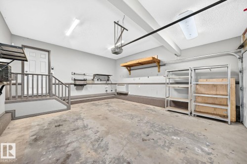 Spacious garage featuring a finished concrete floor, overhead lighting, built-in shelving, and direct access - 217 Silverstone Crescent, Stony Plain, AB - Indoor Photo Showing Garage