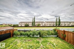 Expansive backyard featuring a wood-panel fence, raised garden beds, and a storage shed with a shingled roof - 