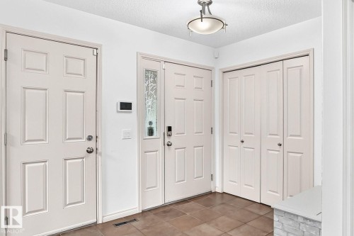 Tiled flooring, multiple paneled doors, decorative glass sidelight, and a flush-mount ceiling light fixture - 217 Silverstone Crescent, Stony Plain, AB - Indoor Photo Showing Other Room