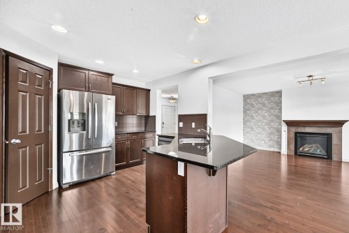 Kitchen and living area featuring dark wood-finish flooring, recessed lighting, and a kitchen island with an undermount sink - 217 Silverstone Crescent, Stony Plain, AB - Indoor Photo Showing Kitchen