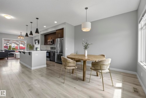 Open-concept living space featuring wood-finish flooring, a kitchen island with pendant lighting, stainless steel appliances, and a window with natural light - 45 Joyal Way, St. Albert, AB - Indoor