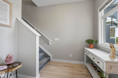 Wood-finish flooring, staircase with carpeted treads and white handrail, and a large window with white trim - 45 Joyal Way, St. Albert, AB - Indoor Photo Showing Other Room