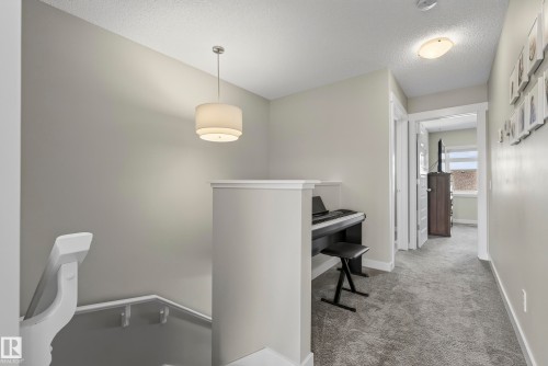 Upper-level hallway with carpeted flooring, white trim, and a contemporary pendant light fixture - 45 Joyal Way, St. Albert, AB - Indoor Photo Showing Other Room