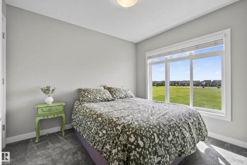 Wall-to-wall carpeting and neutral wall tones complement the large window with white trim, allowing natural light to illuminate the space - 45 Joyal Way, St. Albert, AB - Indoor Photo Showing Bedroom