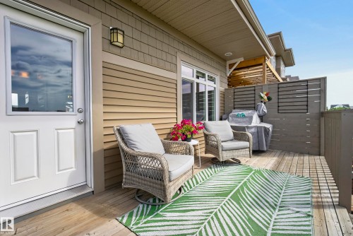 Outdoor deck featuring wood-finish flooring, a privacy screen, and a wall-mounted light fixture - 45 Joyal Way, St. Albert, AB - Outdoor With Deck Patio Veranda With Exterior