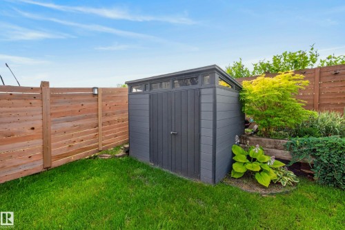 Manicured lawn with a privacy fence, dark gray shed, and tiered landscaping - 45 Joyal Way, St. Albert, AB - Outdoor