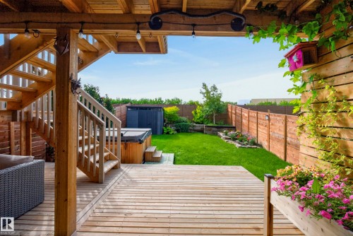 Tiered wood deck with built-in spa, wood-plank fencing, and a manicured lawn - 45 Joyal Way, St. Albert, AB - Outdoor With Deck Patio Veranda With Exterior