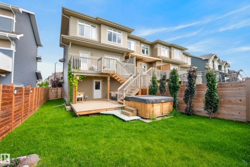 Manicured lawn with a wooden fence, featuring a multi-level wooden deck with stairs and an integrated hot tub - 45 Joyal Way, St. Albert, AB - Outdoor With Deck Patio Veranda With Exterior