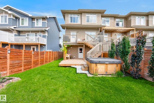 Expansive backyard featuring a lush lawn, a wood-finish fence, and a wooden deck with a built-in hot tub - 45 Joyal Way, St. Albert, AB - Outdoor