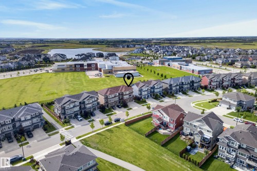 Aerial perspective featuring a residential street, a large green field, a body of water, and surrounding neighborhood homes - 45 Joyal Way, St. Albert, AB - Outdoor With View