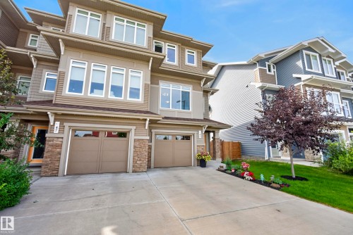 Modern facade with multiple windows, attached two-car garage, stone accents, and a concrete driveway - 45 Joyal Way, St. Albert, AB - Outdoor With Facade