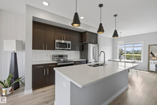 Open-concept kitchen featuring dark wood-finish cabinetry, stainless steel appliances, and a white subway tile backsplash - 45 Joyal Way, St. Albert, AB - Indoor Photo Showing Kitchen With Double Sink With Upgraded Kitchen