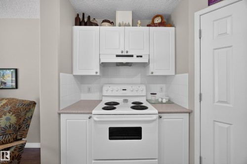 Kitchen area featuring white cabinetry with brushed nickel hardware, a white electric range, and a white tile backsplash - #7 155 Crocus Cr, Sherwood Park, AB - Indoor Photo Showing Kitchen