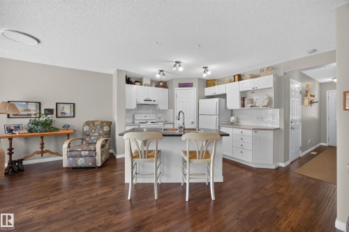 Open concept kitchen featuring white cabinetry, a kitchen island with seating, dark countertops, white subway tile backsplash, and stainless steel appliances - #7 155 Crocus Cr, Sherwood Park, AB - Indoor