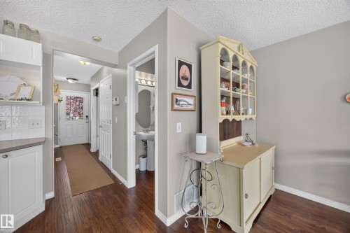 Hallway featuring dark wood-finish flooring, light grey painted walls, white trim, and a white front entry door with a decorative glass insert - #7 155 Crocus Cr, Sherwood Park, AB - Indoor