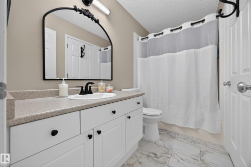 Bathroom featuring a single vanity with white cabinetry, a light speckled countertop, and a white integrated sink with a matte black faucet - #7 155 Crocus Cr, Sherwood Park, AB - Indoor Photo Showing Bathroom