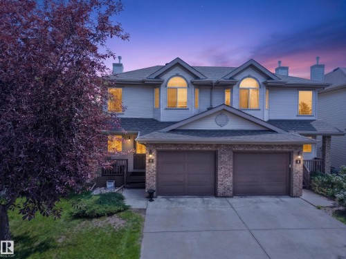 Two-story residence featuring light-colored siding, a two-car garage with brick-finish accents, and multiple dormer windows - #7 155 Crocus Cr, Sherwood Park, AB - Outdoor With Facade