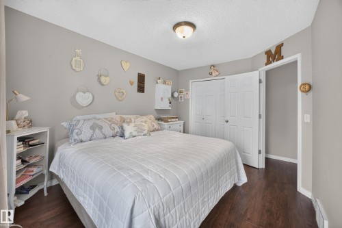 Spacious room featuring wood-finish flooring, light gray wall paint, white trim, and a white bi-fold closet door - #7 155 Crocus Cr, Sherwood Park, AB - Indoor Photo Showing Bedroom