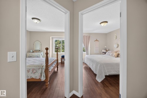 Two distinct bedrooms, each featuring wood-finish flooring and neutral wall tones - #7 155 Crocus Cr, Sherwood Park, AB - Indoor Photo Showing Bedroom
