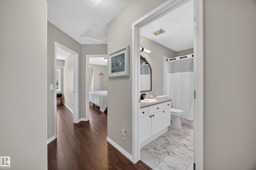 Hallway with wood-finish flooring and light neutral wall tones, providing access to a bathroom and other rooms - #7 155 Crocus Cr, Sherwood Park, AB - Indoor