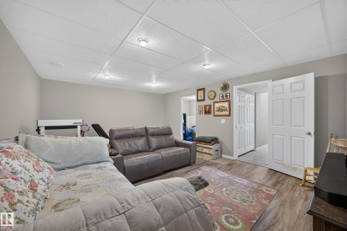 Open-concept living area with wood-finish flooring, drop ceiling with recessed lighting, and neutral wall tones - #7 155 Crocus Cr, Sherwood Park, AB - Indoor Photo Showing Other Room