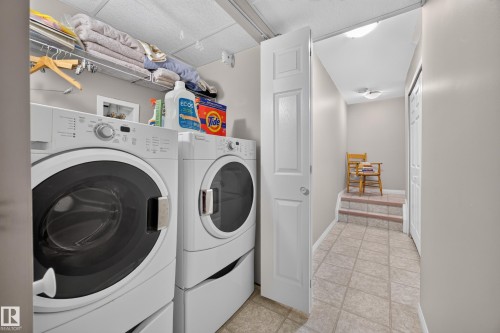 Dedicated laundry area featuring front-loading washer and dryer units, overhead wire shelving for storage, and light-toned wall paint - #7 155 Crocus Cr, Sherwood Park, AB - Indoor Photo Showing Laundry Room