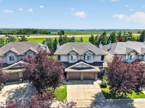 Two-story residence featuring a two-car garage, dormer windows, a gabled entry, mature landscaping, and a paved driveway - #7 155 Crocus Cr, Sherwood Park, AB - Outdoor With Facade
