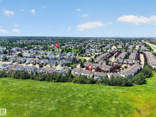 Expansive green space bordering a residential neighborhood with detached homes and townhomes, featuring mature trees and clear skies - #7 155 Crocus Cr, Sherwood Park, AB - Outdoor With View