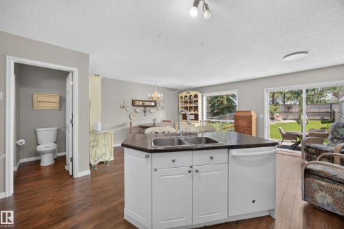 Kitchen island with white cabinetry, a double basin sink, and a dark countertop - #7 155 Crocus Cr, Sherwood Park, AB - Indoor Photo Showing Kitchen With Double Sink