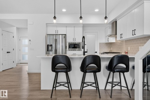 Kitchen island with three pendant lights and a stainless steel appliance suite - 23027 96 Avenue Nw, Edmonton, AB - Indoor Photo Showing Kitchen With Stainless Steel Kitchen With Upgraded Kitchen