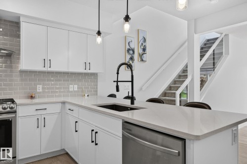 Modern kitchen featuring white cabinetry, light countertops, a subway tile backsplash, and stainless steel appliances - 23027 96 Avenue Nw, Edmonton, AB - Indoor Photo Showing Kitchen With Upgraded Kitchen