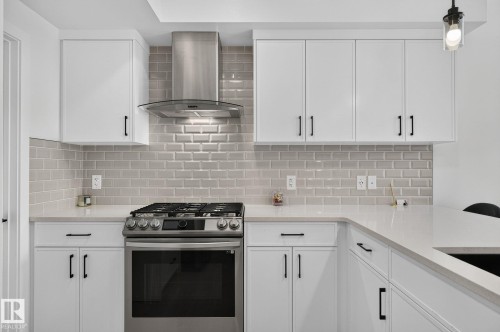 Modern kitchen featuring white cabinetry, light-toned countertops, a stainless steel range, a matching range hood, and a light-toned subway tile backsplash - 23027 96 Avenue Nw, Edmonton, AB - Indoor Photo Showing Kitchen With Upgraded Kitchen