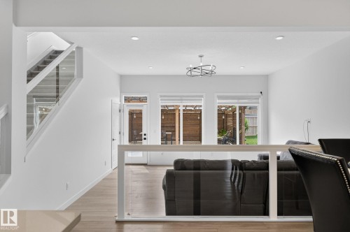 Open-concept living area with wood-finish flooring, a contemporary chandelier, and recessed lighting - 23027 96 Avenue Nw, Edmonton, AB - Indoor