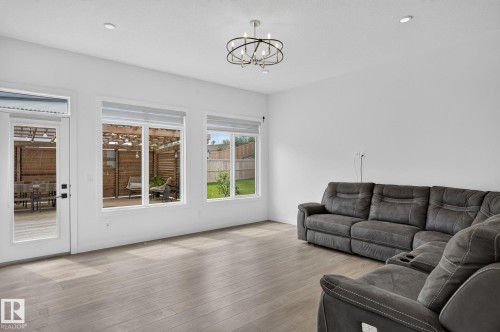 Living area featuring wood-finish flooring, recessed lighting, and a contemporary chandelier - 23027 96 Avenue Nw, Edmonton, AB - Indoor Photo Showing Living Room