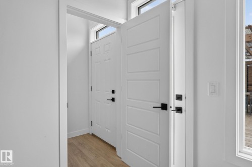 Entryway featuring a white paneled door with matte black hardware, wood-finish flooring, and transom windows - 23027 96 Avenue Nw, Edmonton, AB - Indoor Photo Showing Other Room