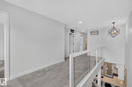 Upper level hallway featuring grey carpeting, recessed lighting, and a modern geometric pendant light fixture - 23027 96 Avenue Nw, Edmonton, AB - Indoor