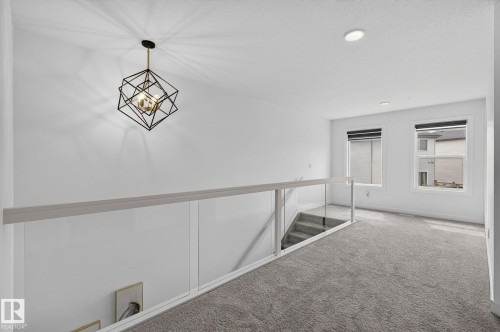 Loft space featuring a modern geometric chandelier, glass railing, recessed lighting, and two windows - 23027 96 Avenue Nw, Edmonton, AB - Indoor Photo Showing Other Room