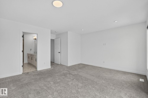 Spacious carpeted room featuring a ceiling-mounted light fixture, recessed lighting, and white walls - 23027 96 Avenue Nw, Edmonton, AB - Indoor Photo Showing Other Room