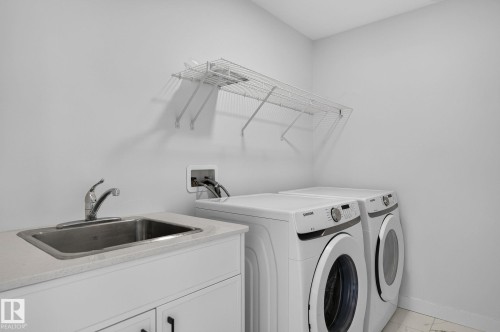 Dedicated laundry area featuring a utility sink with a chrome faucet, white cabinetry, a light-colored countertop, and a wall-mounted wire shelf - 23027 96 Avenue Nw, Edmonton, AB - Indoor Photo Showing Laundry Room