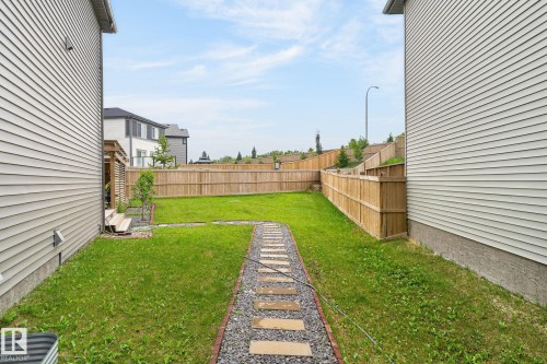 Expansive backyard featuring a central stepping stone pathway, manicured lawn, and natural wood privacy fencing - 23027 96 Avenue Nw, Edmonton, AB - Outdoor