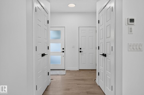 Entryway featuring wood-finish flooring, white paneled doors with matte black hardware, and a modern door with frosted glass panels - 23027 96 Avenue Nw, Edmonton, AB - Indoor Photo Showing Other Room