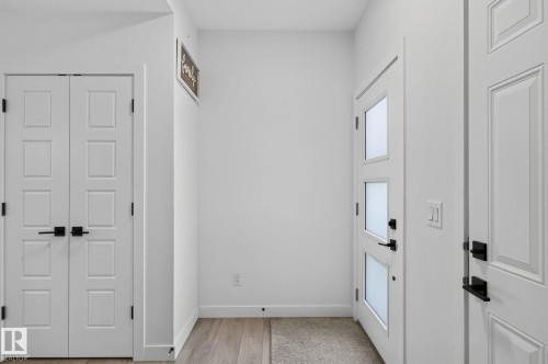 Bright entry area featuring a three-panel door with frosted glass inserts, matte black hardware, and wood-finish flooring - 23027 96 Avenue Nw, Edmonton, AB - Indoor Photo Showing Other Room