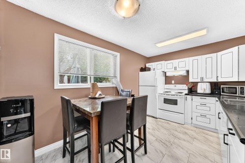 Kitchen featuring white cabinetry, dark countertops, a window with blinds, and light-toned flooring - 64 Habitat Crescent Nw, Edmonton, AB - Indoor Photo Showing Kitchen