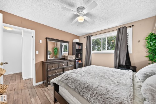 Wood-finish flooring, ceiling fan with integrated lighting, built-in shelving, and a large window - 64 Habitat Crescent Nw, Edmonton, AB - Indoor Photo Showing Bedroom